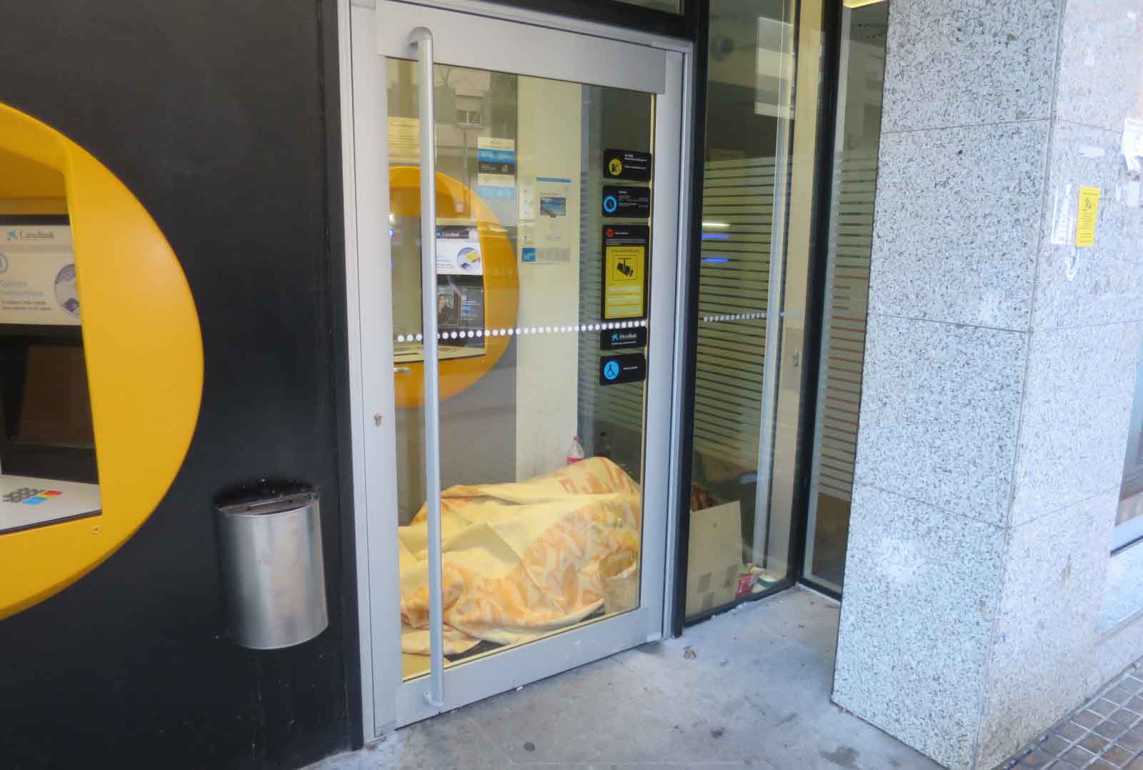 Una pareja duerme en un cajero de Alfonso IX, este domingo a las 17 horas.