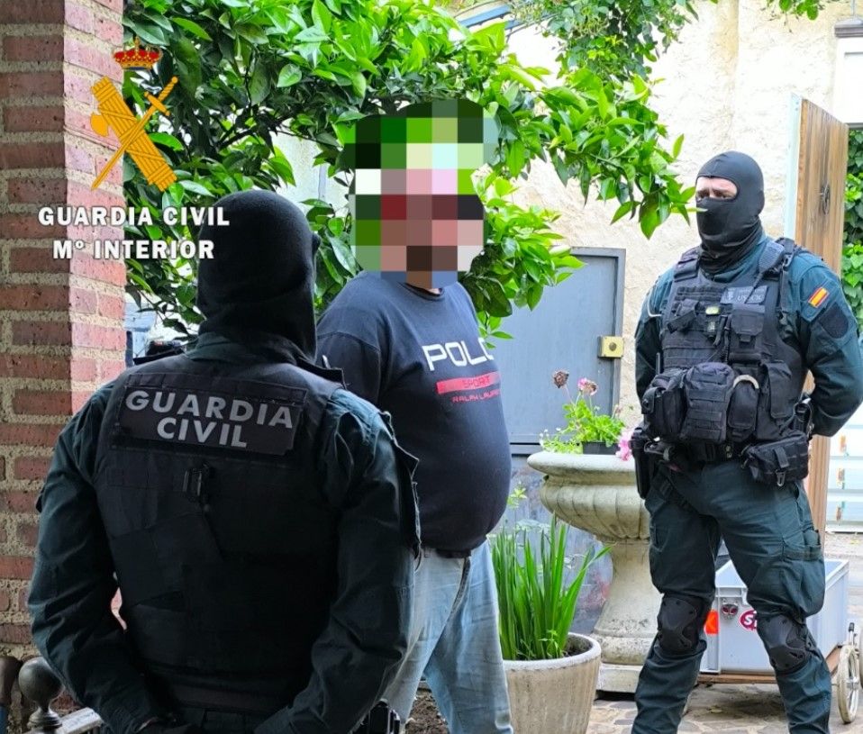 Dos guardias civiles custodian al detenido en Cepeda.