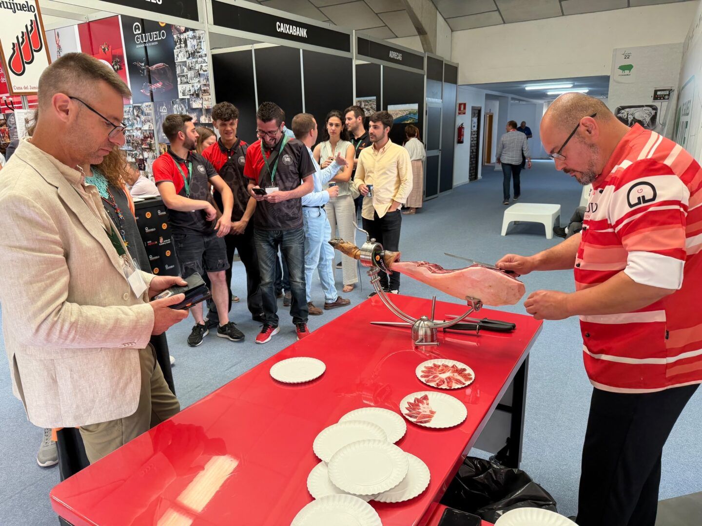 Expositores y visitantes en el puesto de la degustación de jamón ibérico.