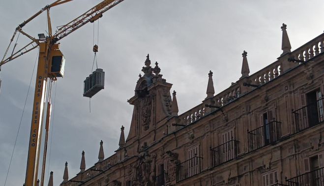 La grúa sube el equipo por encima de las cubiertas de la Plaza Mayor. Fotografía. Pablo de la Peña. La grúa sube el equipo por encima de las cubiertas de la Plaza Mayor. Fotografía. Pablo de la Peña.
