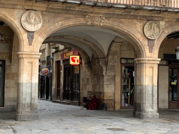 Una persona pidiendo en el arco de la calle Prior, en Salamanca.