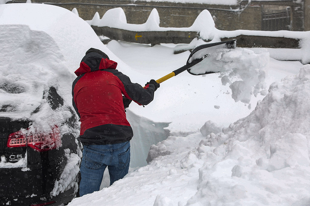Campillo. ICAL. Un hombre retira la gran cantidad de nieve acumulada en su vehículo estacionado en el Puerto de Pajares de León.