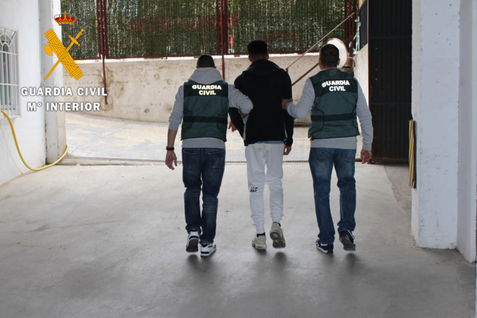 Dos guardias civiles llevan a uno de los detenidos en la estafa telemática.